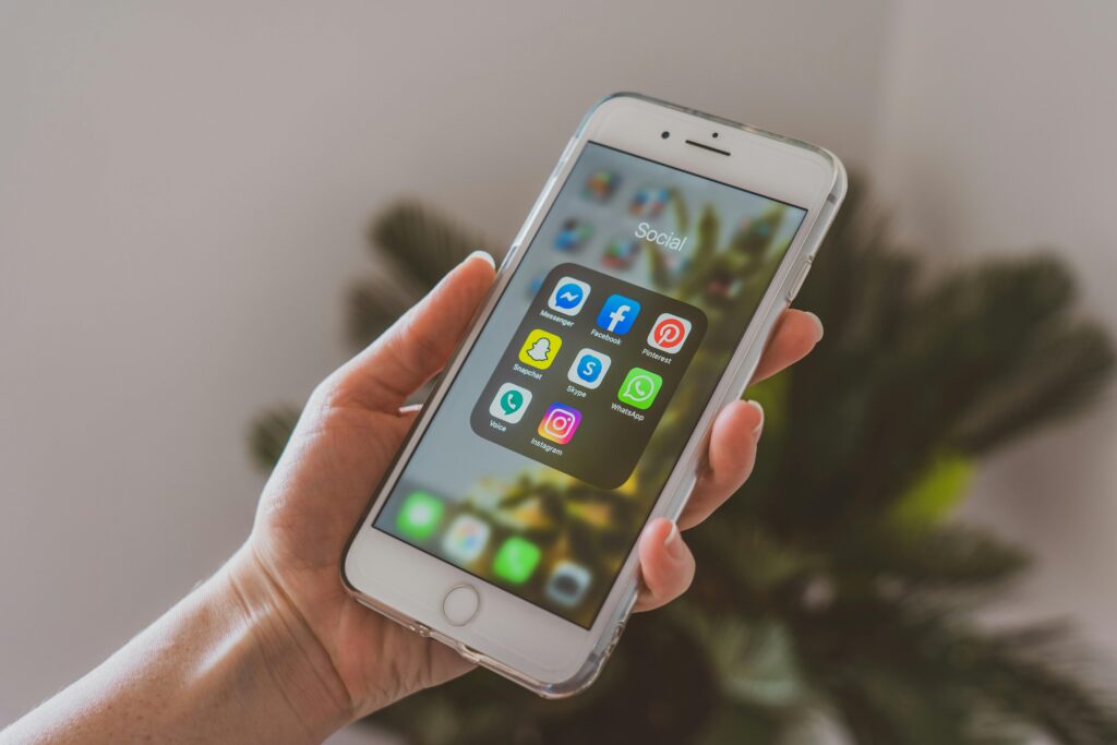 person holding their phone, with their social folder/tab open, showing all their social media icons